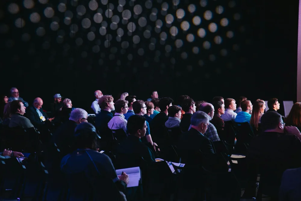 Conference attendees seated in a dark auditorium