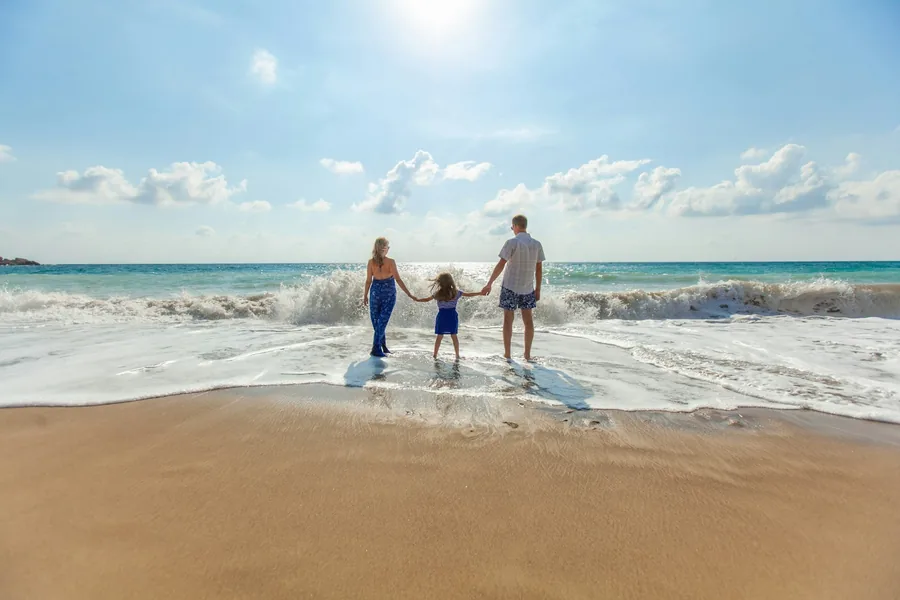 A family holding hands while walking along the shore